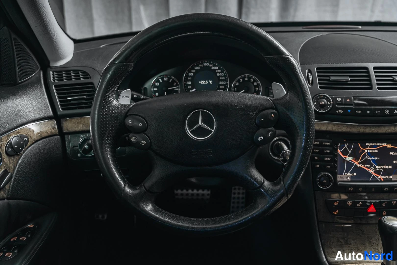 Muu: Ohjauspyörän lähikuva Mercedes-tähtimerkillä, taustalla mittaristo ja navigointinäyttö.