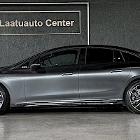 Sivulta: Harmaan Mercedes-Benz EQE -auton sivuprofiili, koko kylki kuvassa oikealta vasemmalle, harmaata showroom-seinää vasten.