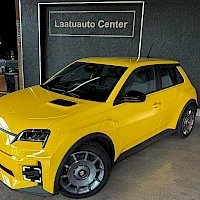 Etuviisto, nokka vasemmalle: Keltainen pikkuauto etuviistosta: etupää ja vasen kylki näkyvät, taustalla Laatuauto Center -kyltti. Kuva on pienikokoinen.