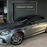 Etuviisto, nokka vasemmalle: Pienikokoinen etukulmanäkymä harmaasta Mercedes-Benz-sedanista sisätilassa.