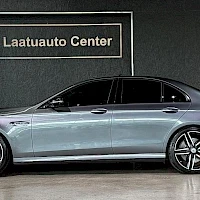 Sivulta: Harmaan Mercedes-Benz-sedanin sivunäkymä etuovesta takarenkaaseen, taustalla Laatuauto Center -kyltti.