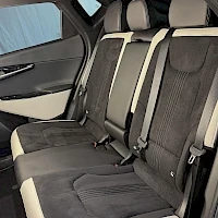 Muu: Auton takaistuinpenkki musta-beige-verhoilulla, kolme niskatukea näkyvissä.