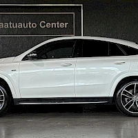 Sivulta: Valkoisen Mercedes-coupémaasturin sivuprofiili; näkyvät ovet, lasitus ja taaempi kevytmetallivanne, taustalla Laatuauto Center -kyltti.