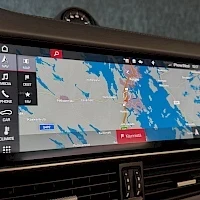 Muu: Keskikonsolin infotainment-näyttö kartta- ja mediavalikoilla, kyljen muovisuojus peilaa kuvaa.