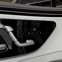 Yksityiskohta: Close-up detail of the door panel controls. A chrome-finished seat adjustment lever is visible next to black buttons for adjusting the seat cushion angle (front