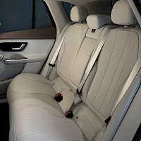 Takaistuimet: Rear interior shot showing the back bench seat in a matching light beige or cream color. Two headrests and seatbelts are clearly visible.