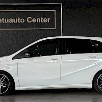 Sivulta: Sivukuva valkoisesta Mercedes-Benz B 200 -autosta; ovet, peilit ja tummat kevytmetallivanteet näkyvissä, taustalla Laatuauto Center -kyltti.