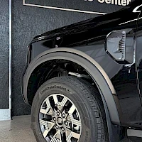 Sivulta: Black Ford Ranger pickup truck close-up of front driver-side wheel and fender with visible alloy wheel and tire tread in indoor setting