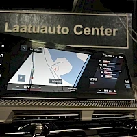 Muu: Dashboard navigation screen showing a map interface; above it, a sign reads Laatuauto Center