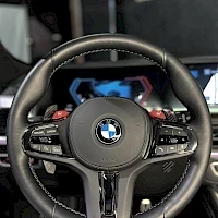 Muu: Lähikuva BMW-ohjauspyörästä, jossa on punaiset M-näppäimet ja merkkitoiminnon näyttö mittaristossa.