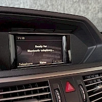 Yksityiskohta: Auton kojelaudan näyttö, jossa teksti 'Ready for Bluetooth Audio' ja valikot 'Telefon/menu' ja 'Hänp'.