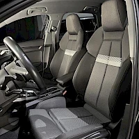 Etuistuimet: Two front sports seats upholstered in dark grey/black material with horizontal silver trim strips. The door sill plate is visible below.