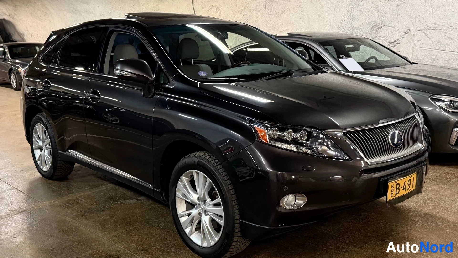 Etuviisto, nokka oikealle: Tumma Lexus RX kulmaesitys vasemmalta edestä, kuva otettu autotallissa.