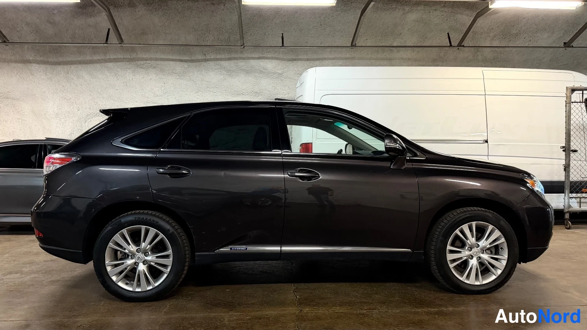 Takaviisto: Tummanruskea Lexus RX -maasturin sivukuva takavalo näkyvissä autotallissa.