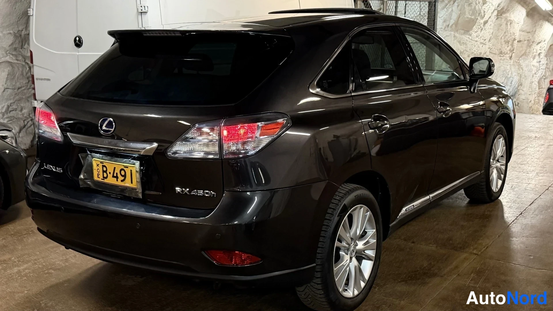 Takaviisto: Tummanruskean Lexus RX 450h:n takaosa ja sivu; kylkikirjoitus Lexus ja taaemman lokasuojan merkintä RX 450h.