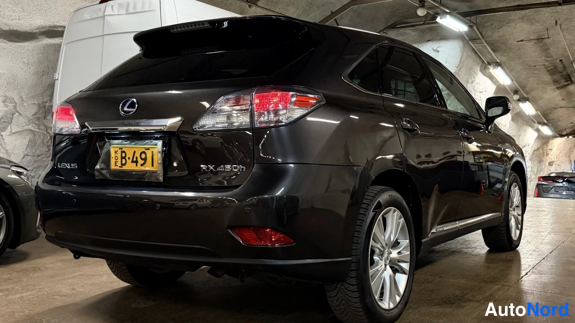Takaviisto: Takaosa-sivunäkymä tummanruskeasta Lexus RX 450h -maasturista tunnelissa.