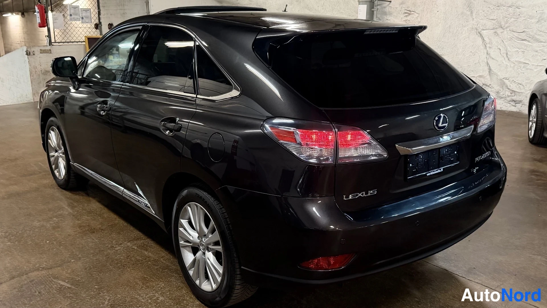 Takaviisto: Mustan Lexusin oikea sivu ja takapuoli autotallissa. Kuvassa näkyvät kromiset kevytmetallivanteet, katon raide, takavalot ja kynnyslista oven alareunassa.