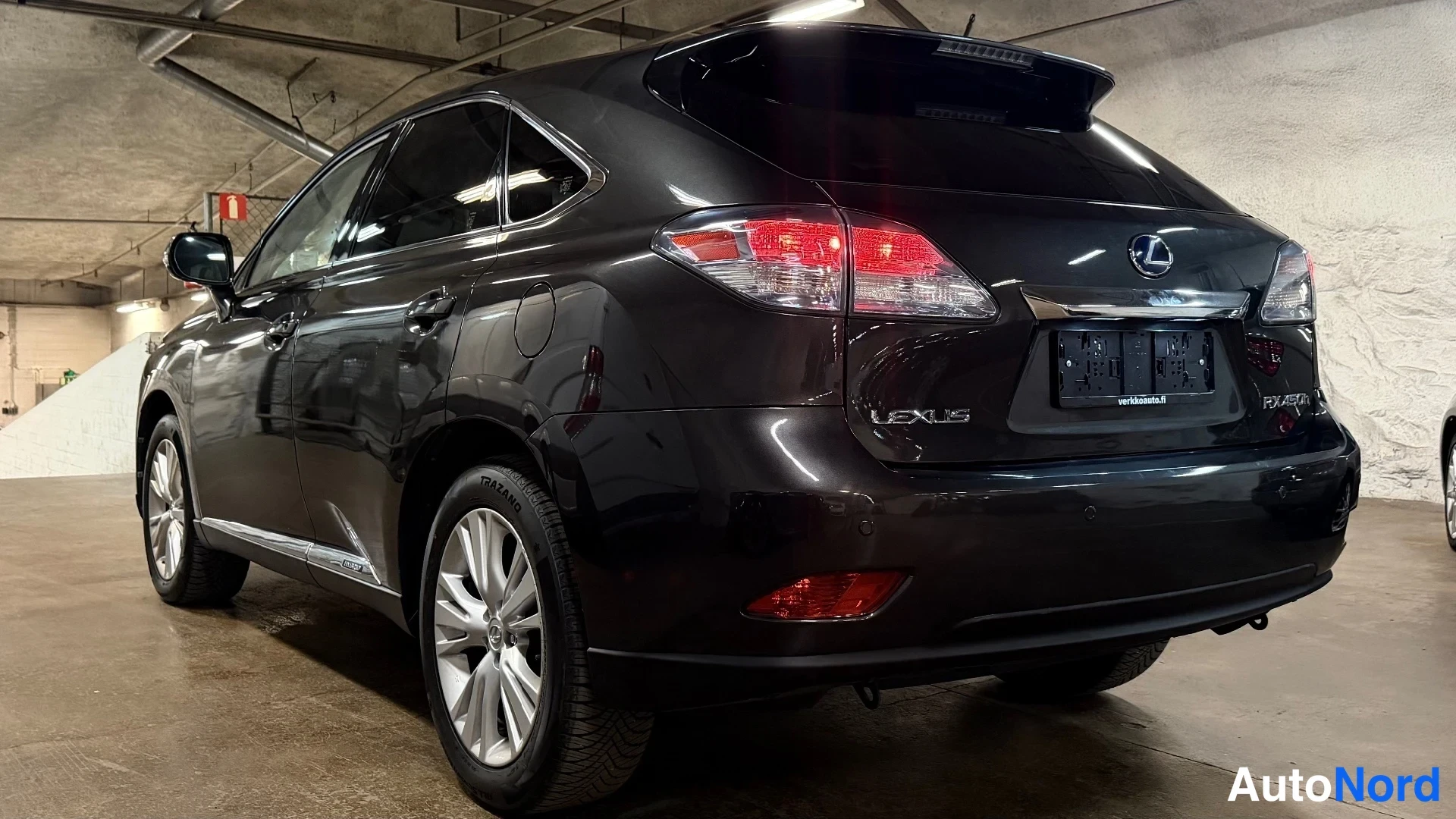Takaviisto: Musta Lexus RX450h:n takavinkeli autotallissa. Selkeästi näkyvät takavalot, katon spoileri, 'LEXUS'- ja 'RX450h'-merkit sekä katonraide.