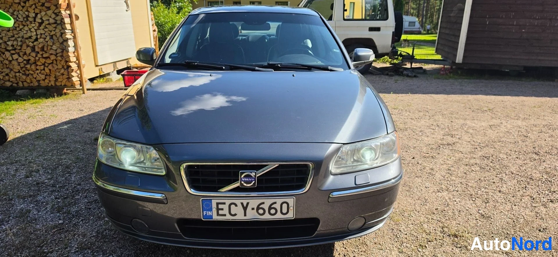 Edestä: Volvo S60:n etunäkymä, rekisterikilpi, auto seisoo sorapihalla.