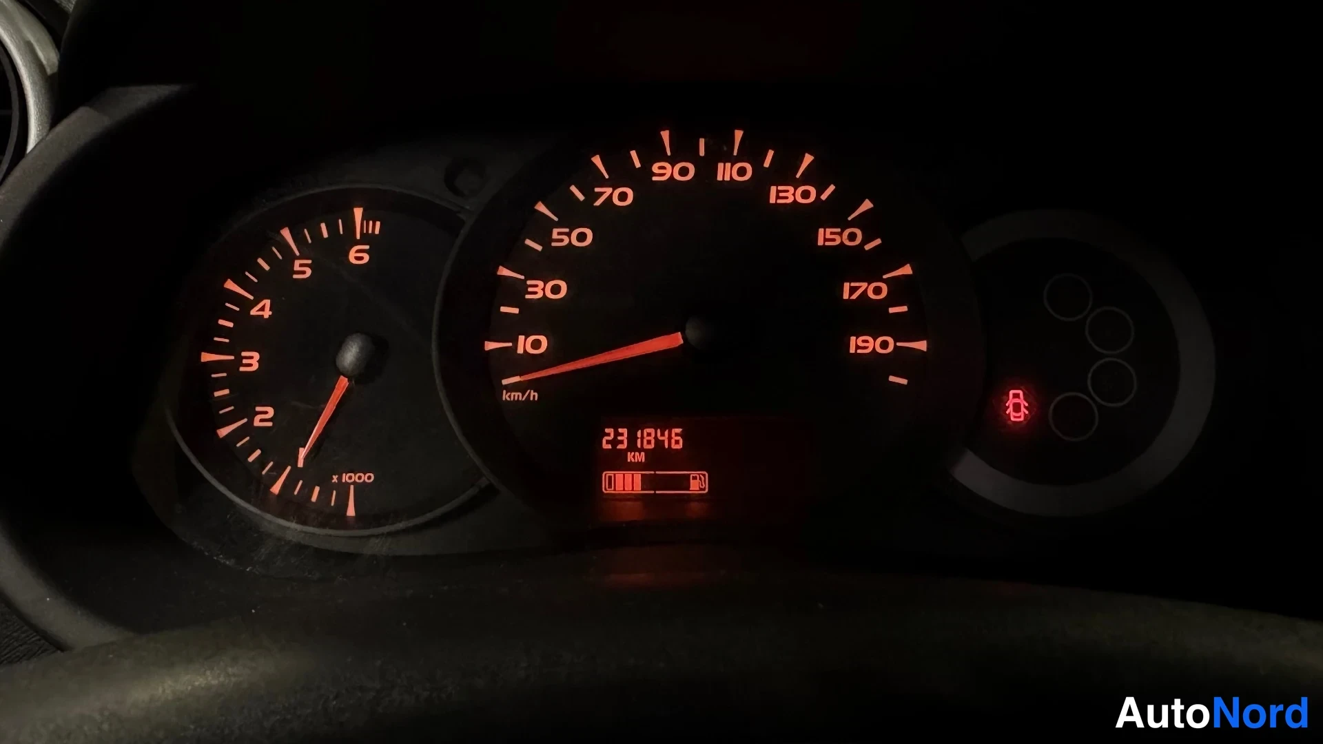 Muu: Mittariston lähikuva pimeässä: kierroslukumittari, nopeusmittari ja matkamittarin lukema 231846 km.