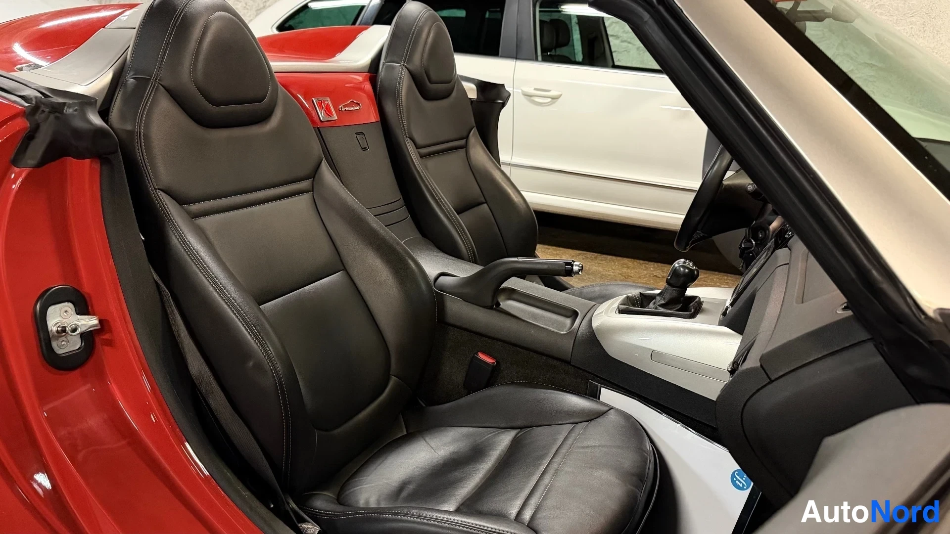 Muu: Mustat nahkaistuimet ja manuaalivaihteen vipu Opel GT:n sisätiloissa, punainen korirakenne näkyvissä.