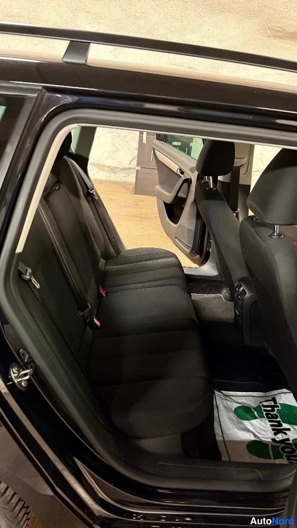Takaistuimet: Rear seat area viewed through the open rear door showing dark fabric bench seat with headrests.