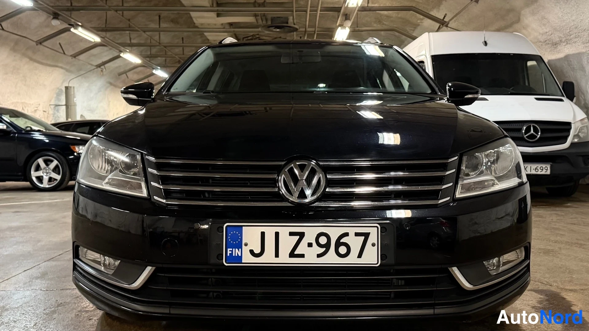 Edestä: Mustan auton etusäleikön lähikuva suoraan edestä, rekisterikilpi.