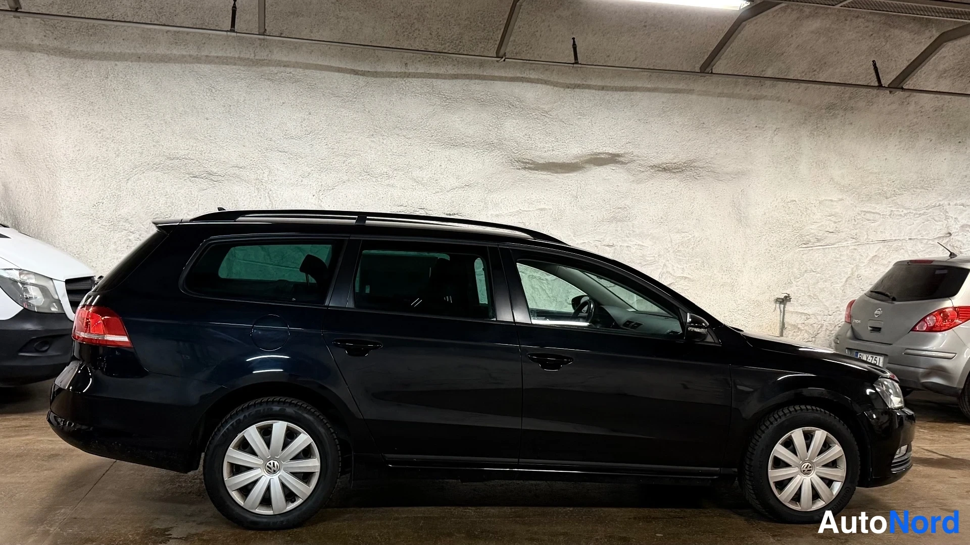 Sivulta: Oikea profiilikuva mustasta Volvo S60 -sesta. Taustalla on valkoinen auto.