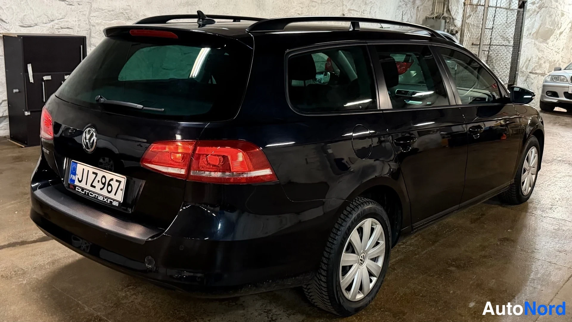 Takaviisto: Takaoikea kolmikulma näytössä musta Volkswagen Passat Variant. Takavalot ja rekisterikilpi ovat selvästi näkyvissä.
