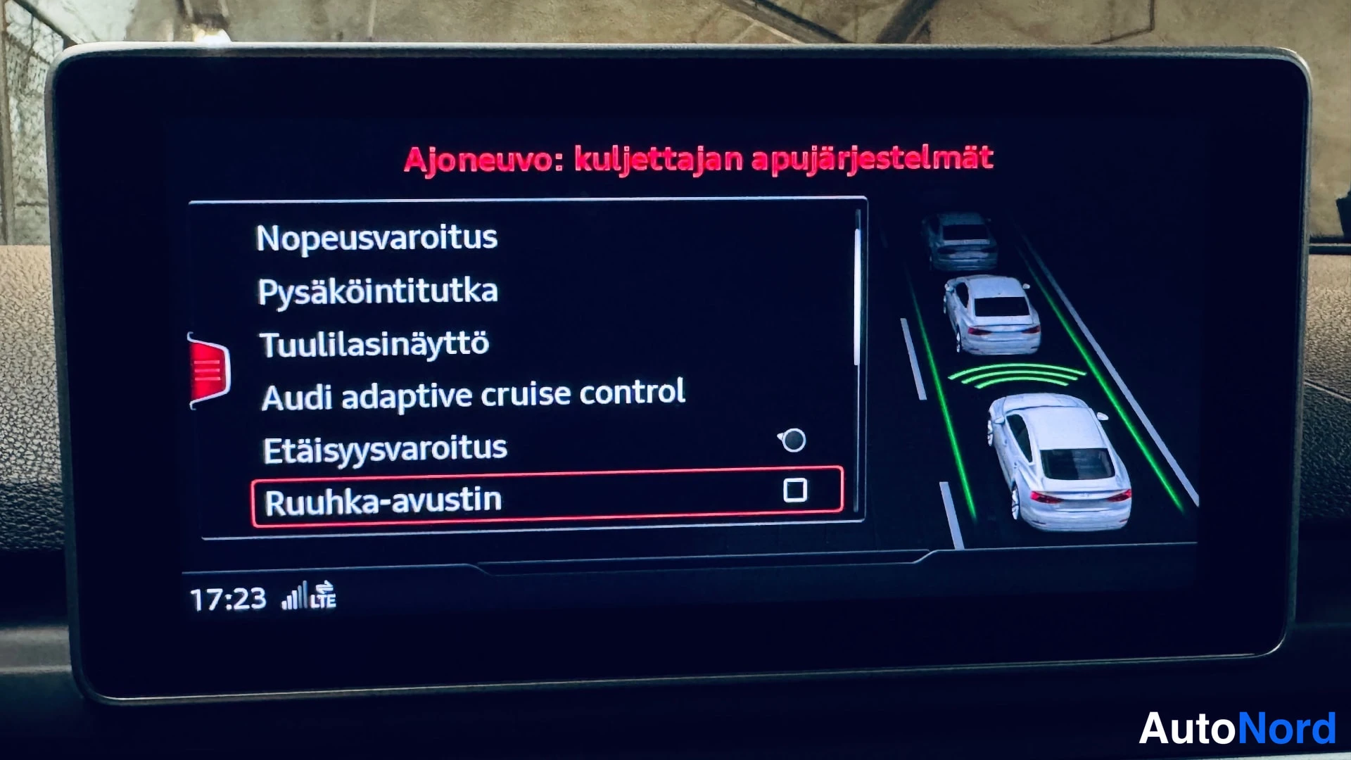 Yksityiskohta: Audin keskikonsolin näyttö näyttää kuljettajan apujärjestelmien valikon, jossa kohteita ovat muun muassa Nopeusvaroitus, Pysäköintitutka, Audi adaptive cruise c