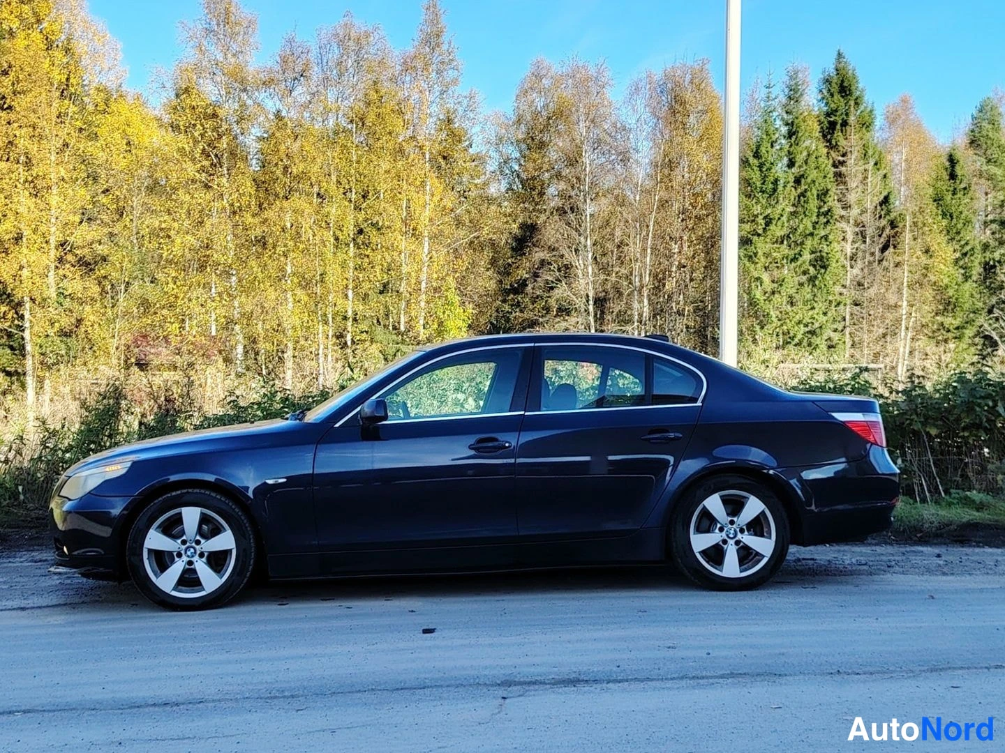 Sivulta: Mustan sininen BMW 5-sarjan sedan sivulta kuvattuna.