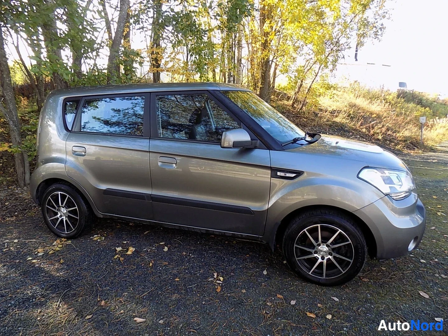 Etuviisto, nokka oikealle: Kia Soul etukulmasta oikealta, harmaa koripaneeli ja keulavalot auringonvalossa.