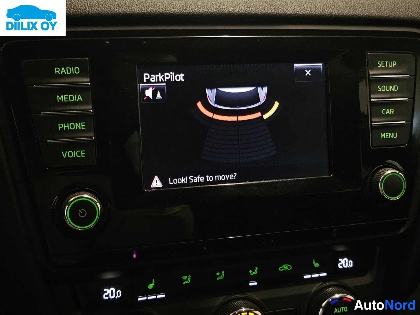 Muu: Kojelaudan keskinäytön lähikuva, jossa näkyy ParkPilot-aluejärjestelmän grafiikka ja ilmoitus 'Look! Safe to move?'. Näytön sivuilla RADIO-, MEDIA-, PHONE- ja V