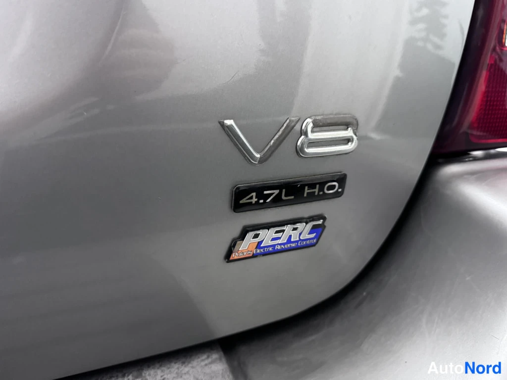 Yksityiskohta: Lähikuva auton perästä: kromattu V8-merkintä, musta 4.7L H.O. -nimikilpi ja sininen PERC-tarra (Parker Electric Reverse Control).