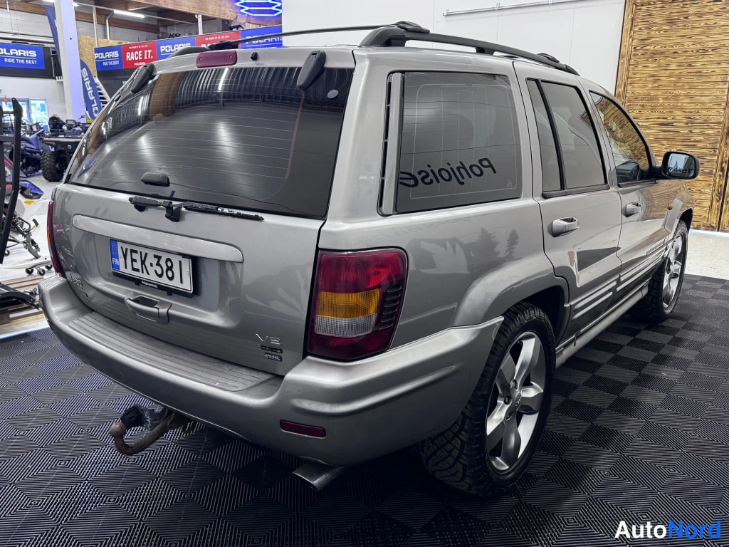 Takaviisto: Hopeanharmaa Jeep&nbsp;Grand Cherokee takaa oikealta kulmasta kuvattuna; näkyvillä rekisterikilpi, V8-merkintä, kattoteline ja vetokoukku.