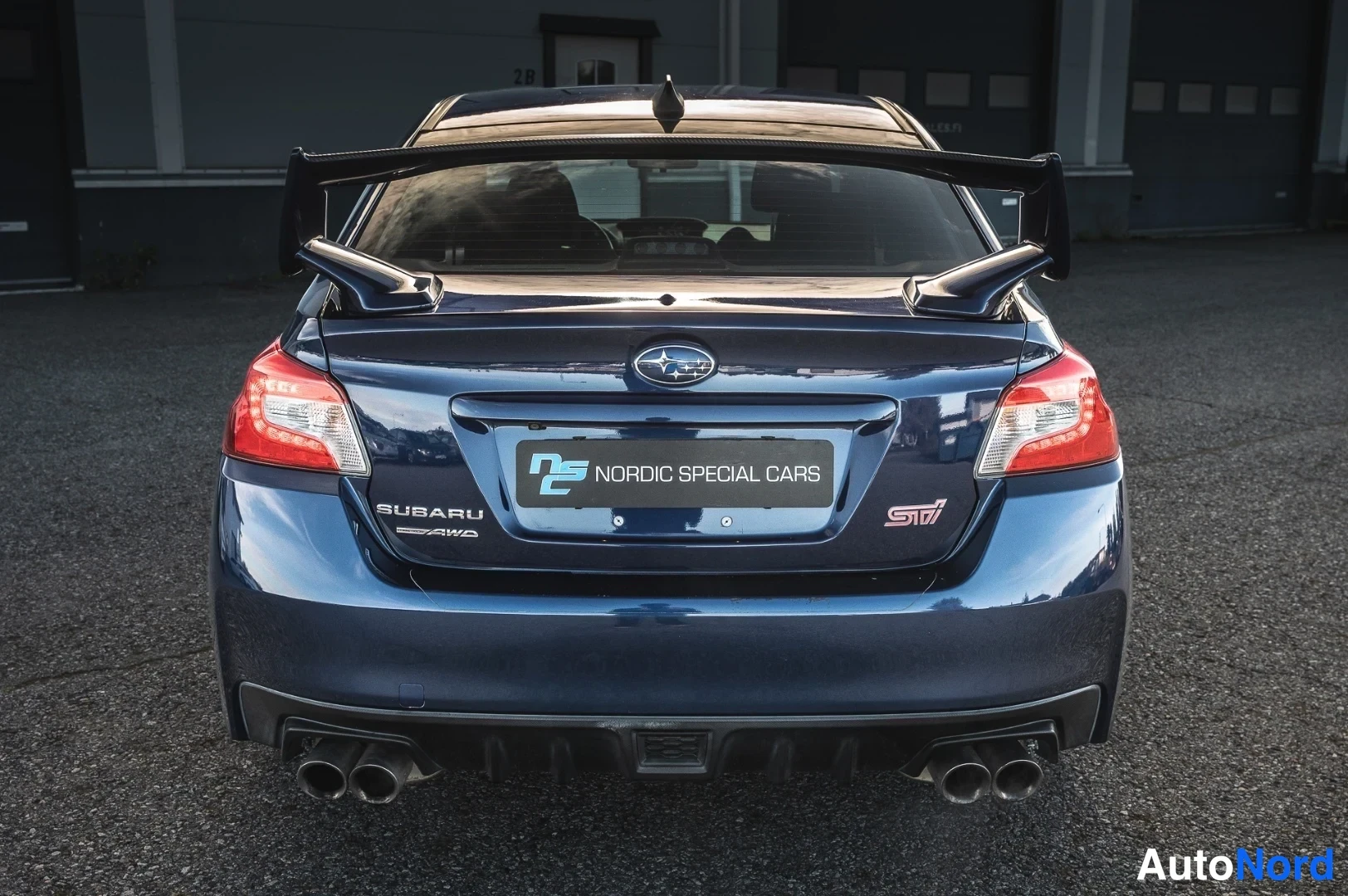 Takaa: Sinisen Subaru-sedan takaosa suoraan takaa, takasiipi ja neljä pakoputkea.