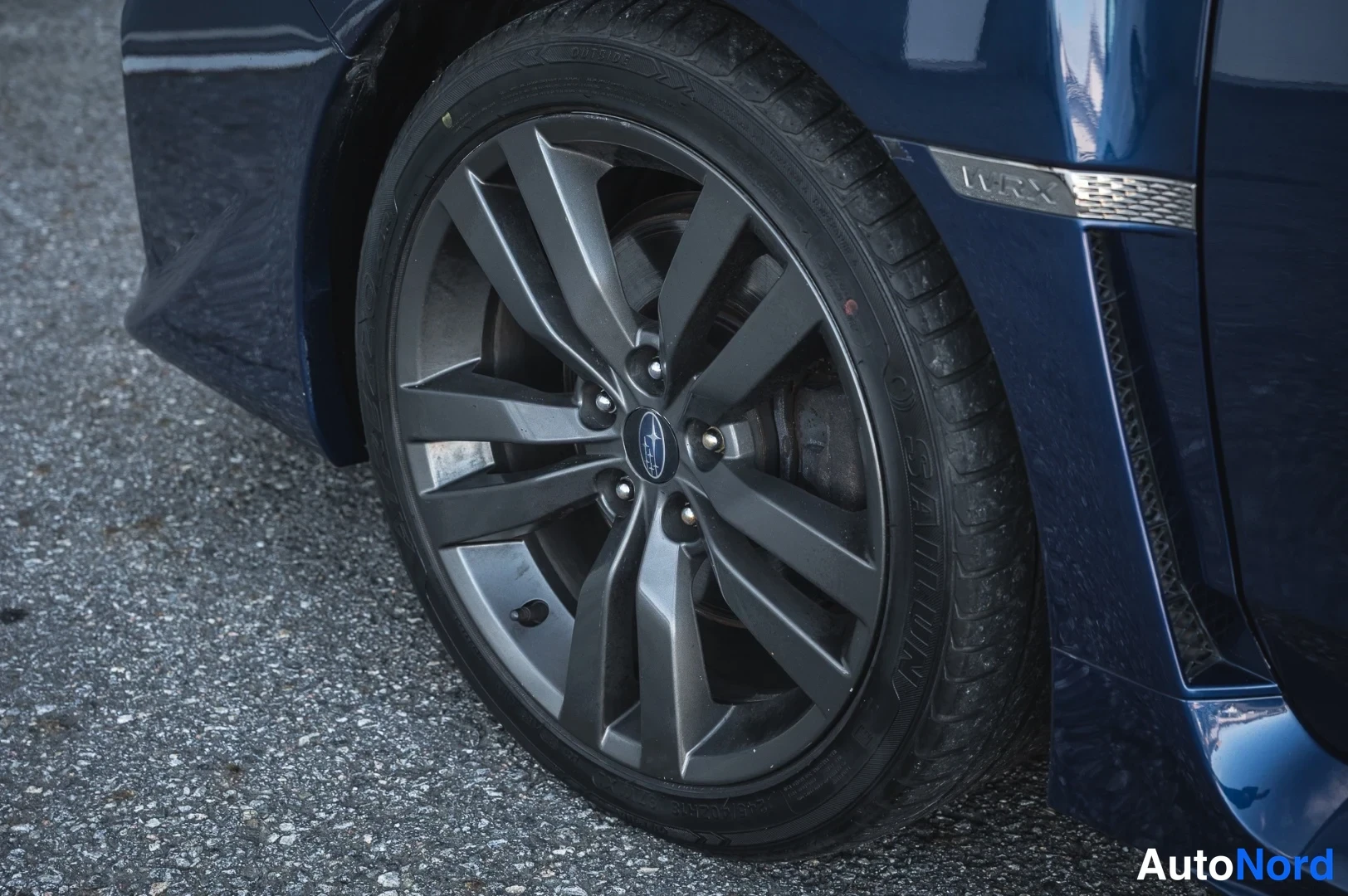 Yksityiskohta: Lähikuva Subaru-merkillisestä tummasta kevytmetallivanteesta ja kesärengas­nastarenkaasta.