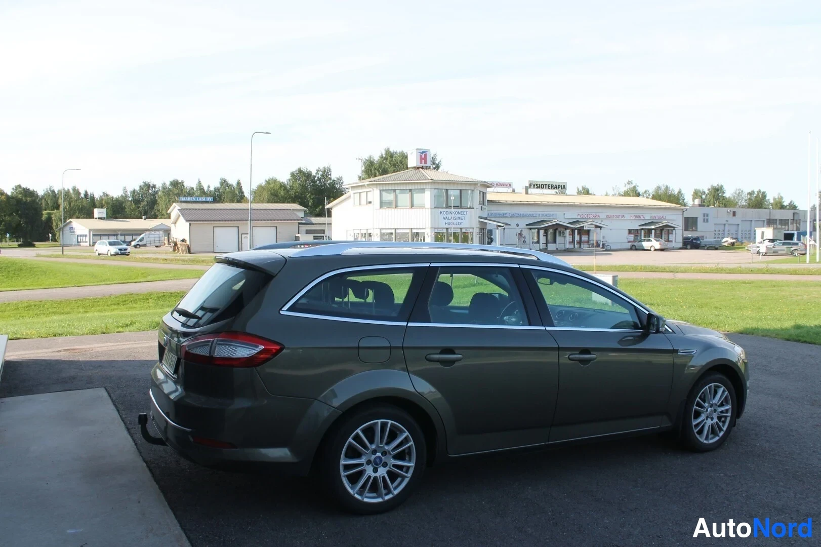 Takaviisto: Ford Mondeo -farmari takaa oikealta, tummanvihreä kori, kattokaiteet ja takavalot näkyvissä.