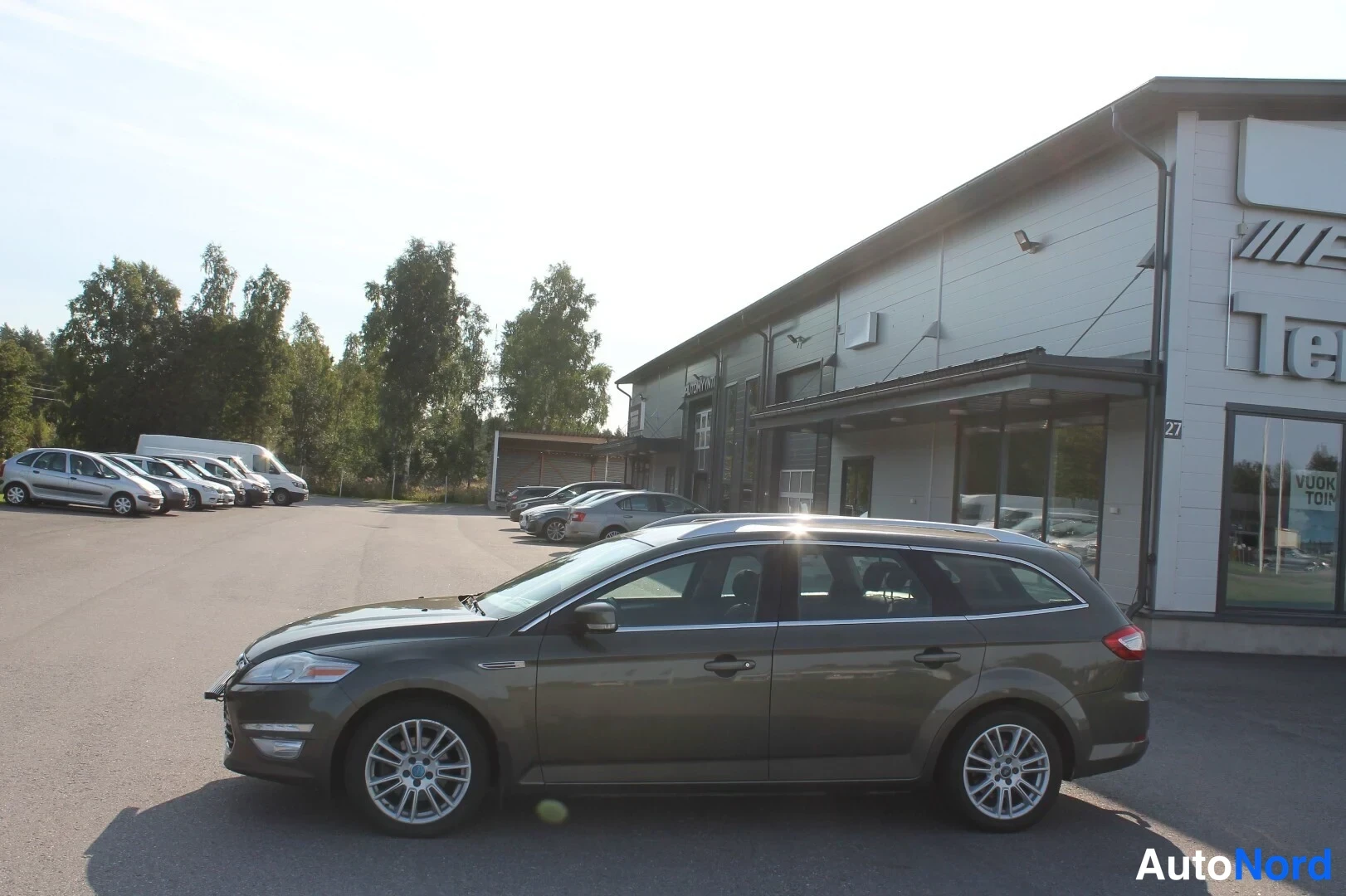 Etuviisto, nokka vasemmalle: Sivulta kolmivartalokuva tummanvihreästä Ford Mondeo -farmarista, keula kuvan vasemmalla puolella.
