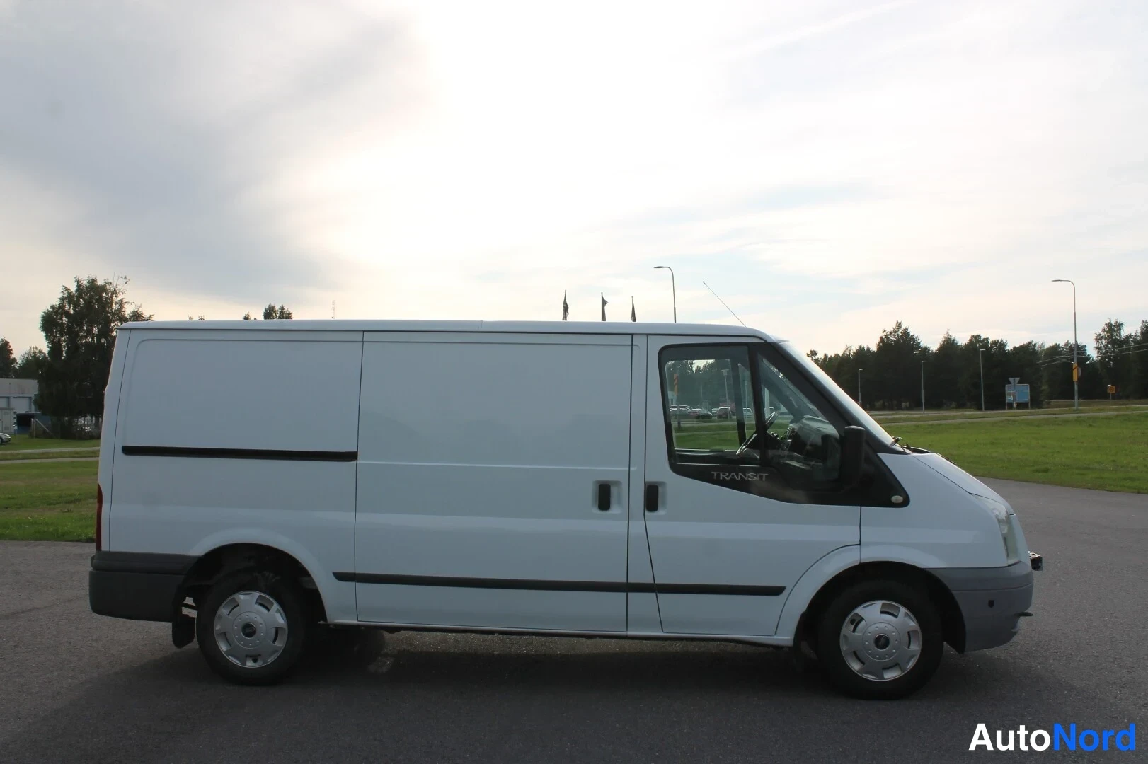 Sivulta: Ford Transit -pakettiauton sivukuva oikealta, valkoinen kori ja sivuliukuovi.
