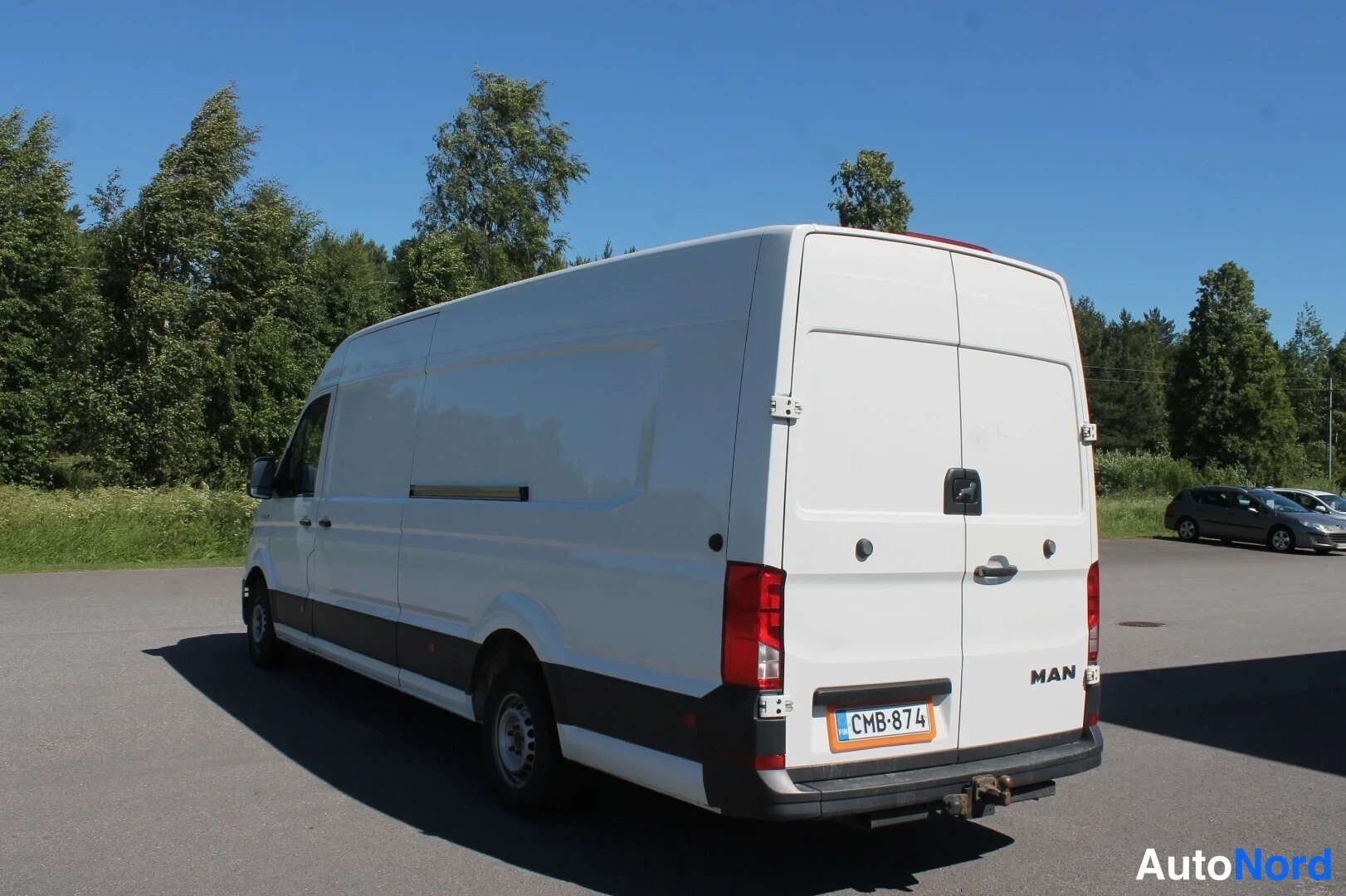 Takaviisto: Valkoisen MAN-pakettiauton takaosa ja oikea kylki parkkipaikalla.