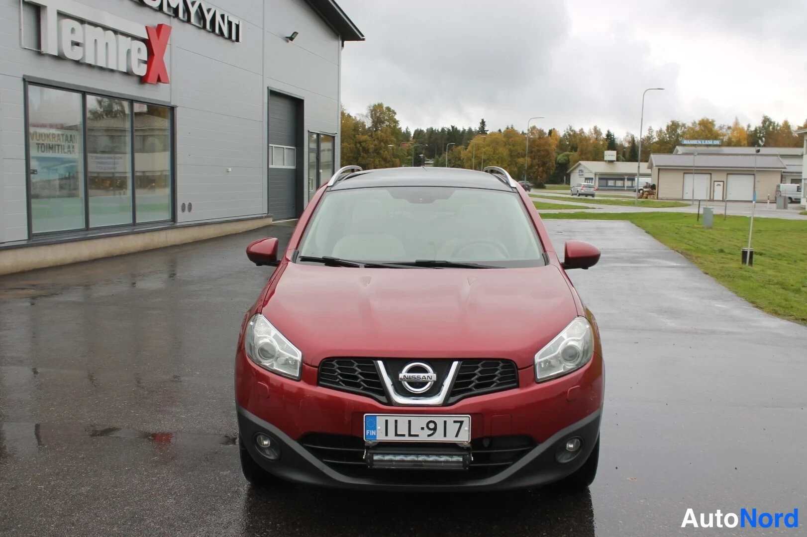 Edestä: Punaisen Nissan Qashqain keula suoraan edestä, rekisteritunnus.