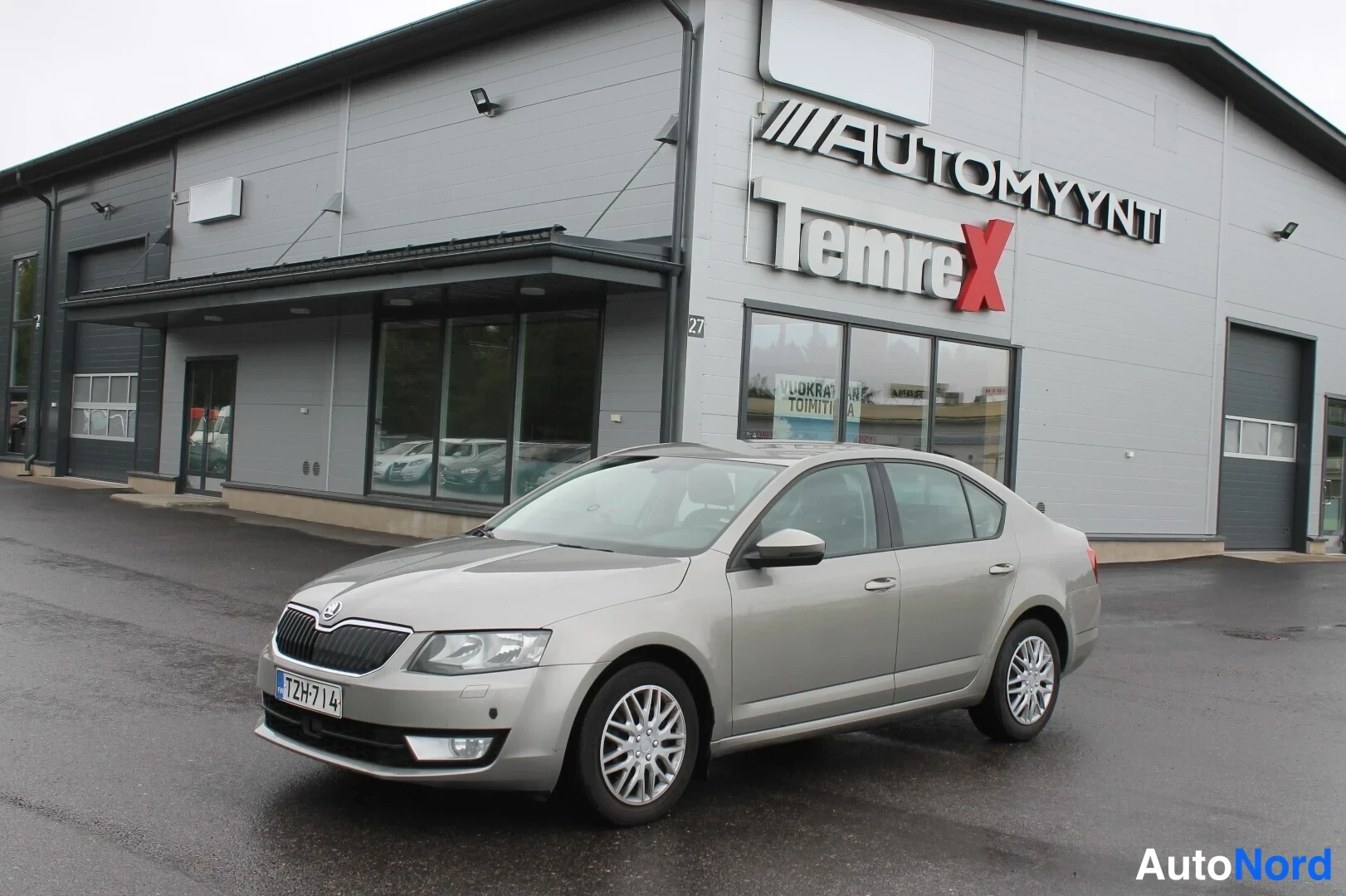 Etuviisto, nokka vasemmalle: Hopeanharmaa Skoda Octavia -sedan etukenokuva liikekiinan edessä.