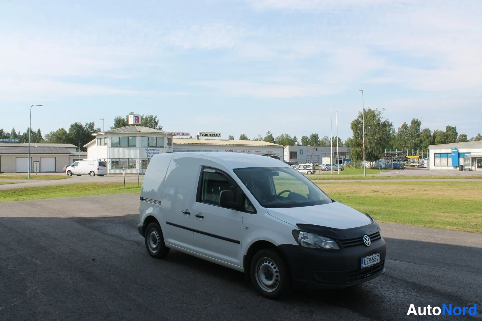 Etuviisto, nokka oikealle: Valkoinen pakettiauto kulmassa edestä oikealta kuvattuna parkkipaikalla.