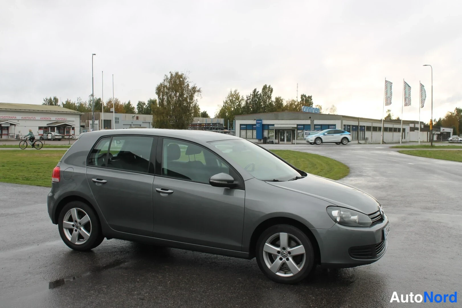 Etuviisto, nokka oikealle: Harmaa Volkswagen Golf viistoperä etusivulta, kevytmetallivanteet ja rekisterikilpi näkyvissä.