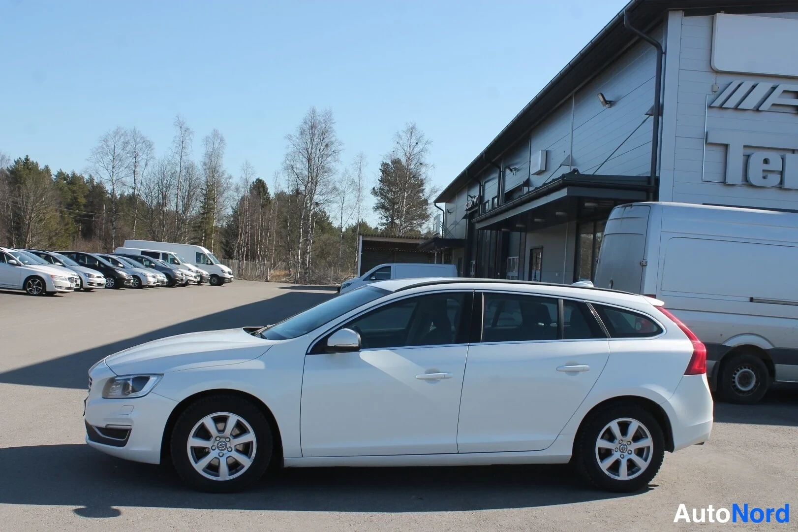 Etuviisto, nokka vasemmalle: Valkoinen farmariauto sivulta edestävasemmalta päin parkkipaikalla.