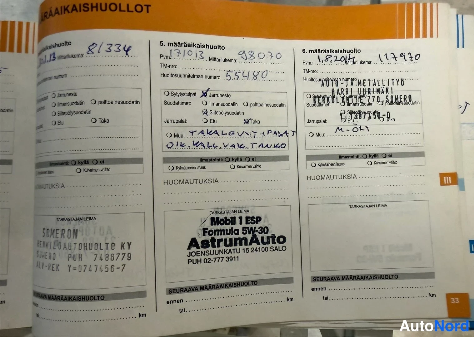 Asiakirja: A close-up photograph of an open vehicle service book page. The page is in Finnish and contains three columns of maintenance records. Three distinct workshop st