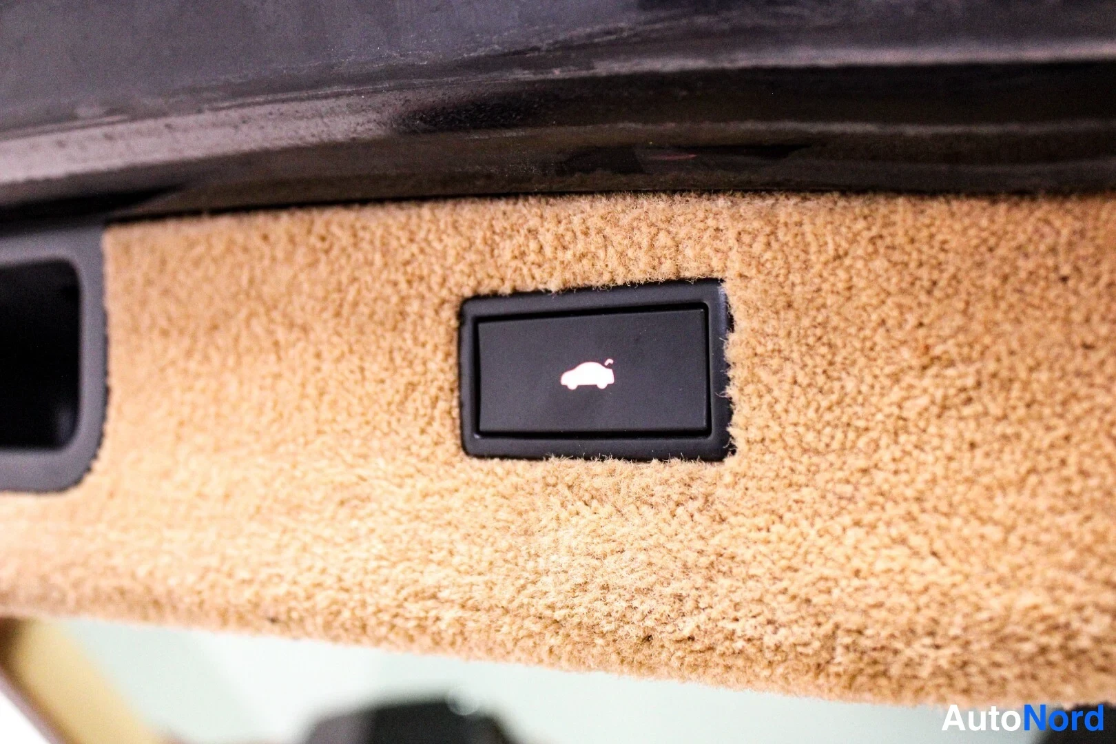 Muu: Sähköostoportin avausnappi luukun sisäpuolella autokolikkeella.
