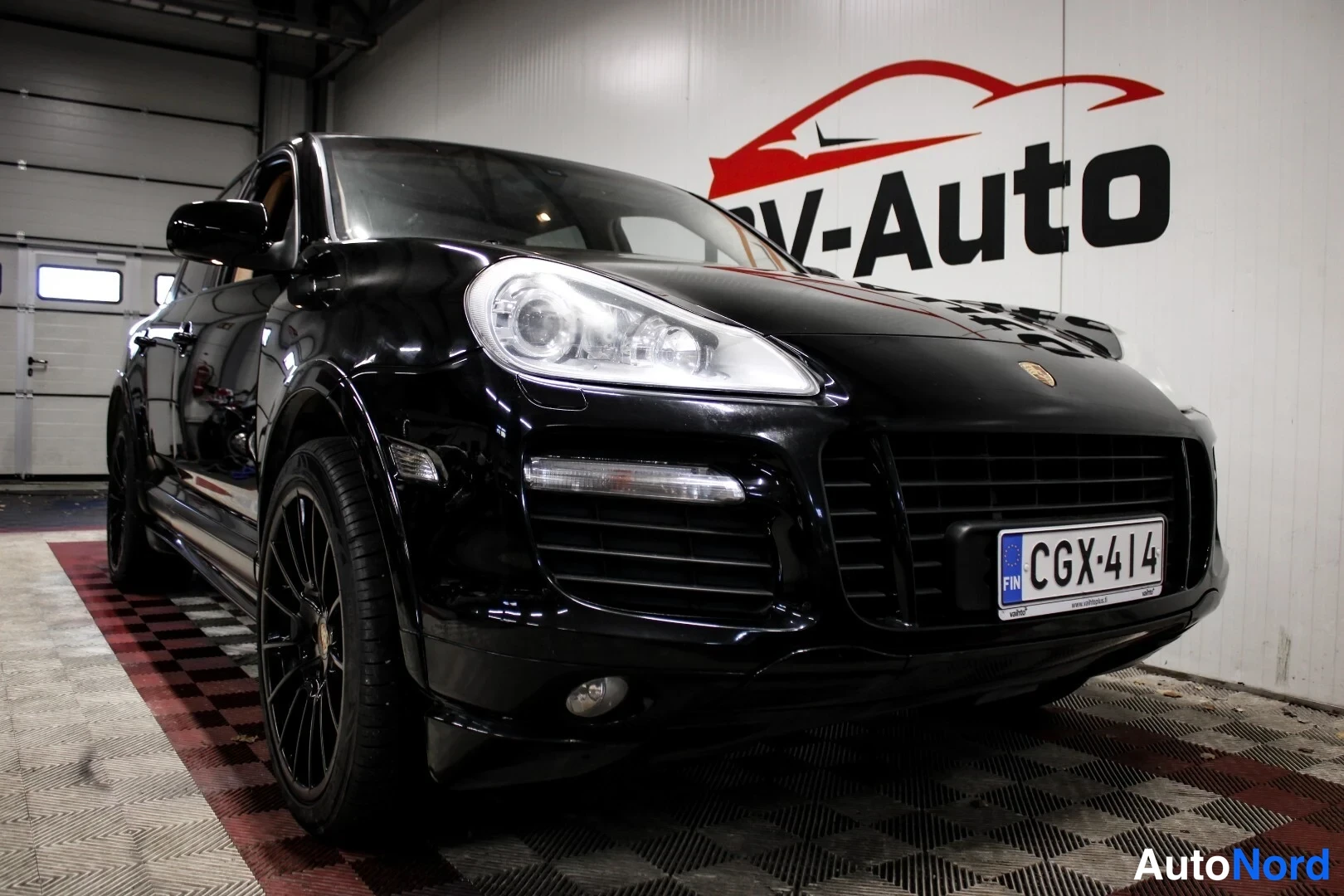Etuviisto, nokka oikealle: Mustan Porsche Cayennen etukulmanäkymä vasemmalta, matala etuspoileri ja rekisteritunnus.