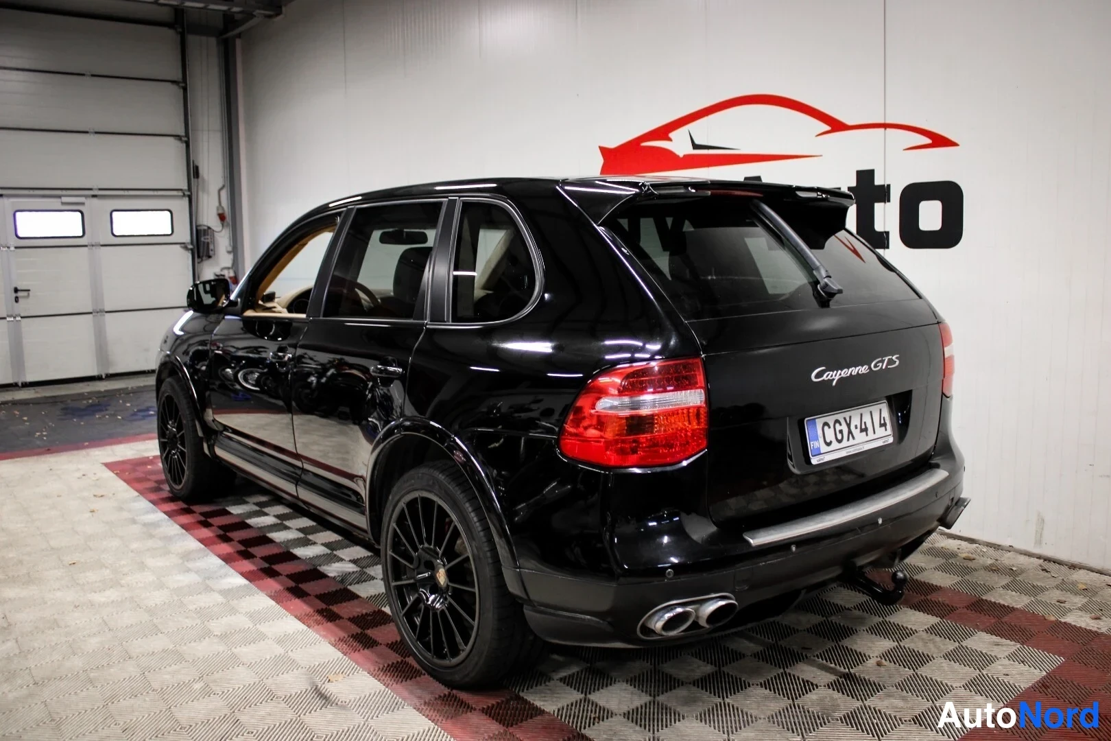 Takaviisto: Porsche Cayenne GTS -farmarivin takakulma autotallissa, musta kori ja takavalot, rekisterikilpi ja takapuskasta näkyväkiekko.